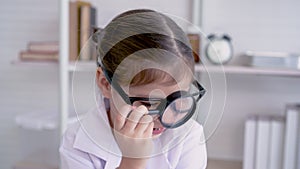 4K, Out of curiosity, a cute young girl is playing with a magnifying glass as a mischievous childhood toy in the school lab.