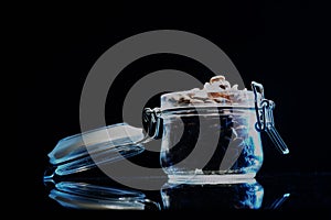 4k. Pine nuts spilled out of a glass jar on black background. Close up.