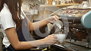 4K. professional barista making a cup of coffee. bartender pouring milk foam in front of coffee maker machine, preparing latte art