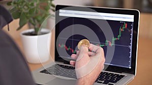 4k resolution of a man`s hand holding bitcoin coin and checking cryptocurrency chart