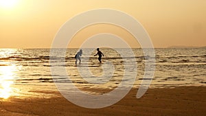 4K. silhouette of sister and brother running and playing in water at the beach on sunset. beauty and joyful teenager friends