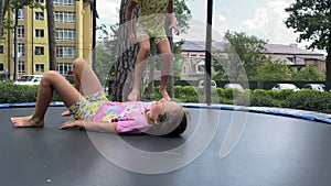 4k Sisters twins jumping on a trampoline in a summertime.