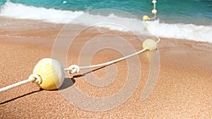 4k slow motion footage of line of plastic buoys connected by rope on the sandy sea beach