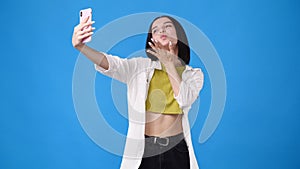 4k slow motion video of beautiful girl making selfie on blue background.