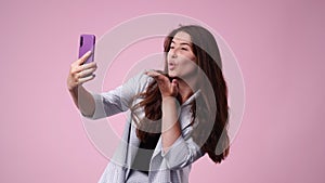 4k slow motion video of one girl making selfie on pink background.