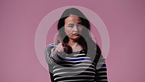 4k slow motion video of one woman who responds negatively to something over pink background.