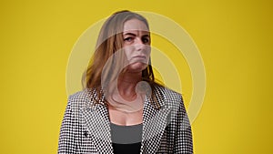 4k slow motion video of one woman who responds negatively to something over yellow background.