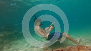 4k Slowmotion shot of young caucasian man snorkeling in a mask and breathing tube in a a beautiful sea with lots of