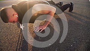 4k still video of young fit man doing push ups in the evening outdoors on road in sunset with strong sun flare