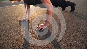 4k still video of young fit man doing push ups in the morning outdoor on road in sunset with strong sun flare