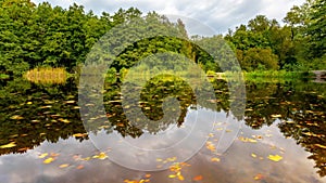 4K time lapse autumn landscape with lake . Colorful foliage park in the fall. Floating leaves and clouds are perfectly reflected i