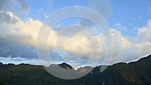 4K Time lapse footage of dramatic cloudscape with blue sky above green mountain range from the afternoon to the evening.