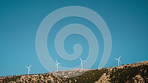4k Time lapse of Wind Mill turbines on top of mountain range against bright blue sky