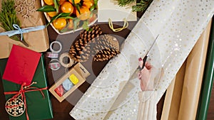 4K Top View of Female Hands Cutting Wrapping Paper for Box with Christmas Gift