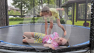 4k Twins girls jumping together on a trampoline.
