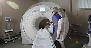 4K Two doctors discuss the patient`s medical history in the CT scan room in a new modern cancer treatment hospital.