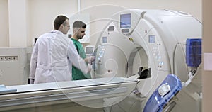 4K Two Doctors presses settings button of CT MRI scanner.