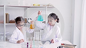 4K, Two little girls in the school lab, interested in a science experiment, raised a bottle of paint out of curiosity. Concept