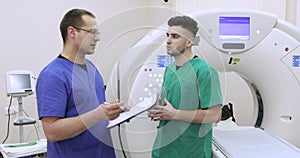 4K Two young doctors discussing the history of the patient on a background of a new magnetic resonance imaging.