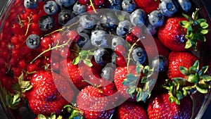 4k. Various colourful berries in glass blow rotation on black background, strawberry, raspberry, blackberry, blueberry, healthy fo