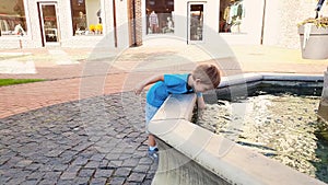 4k video of adorable toddler boy touching water in fountain at park