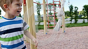 4k video of cute little boy throwing and trying to catch big rope for climbing on playground