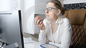 4k video of elegant businesswoman eating red apple in offce during lunch break