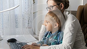 4k video of elegant young businesswoman talking by phone and working at computer while sitting with her baby at office