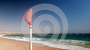 4k video of fluttering red flag on the stormy day at sea beach