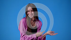 4k video of girl pointing at right side and showing thumb up on blue background.