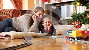 4k video of happy smiling family lying on floor at living room and looking at riding toy train. Child receiving gifts