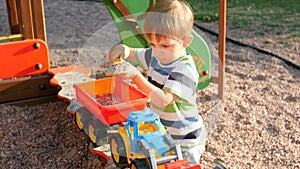 4k video of little concentrated toddler boy playing with trailer and loader in sandbox