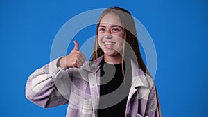 4k video of one girl showing thumb up over blue background.