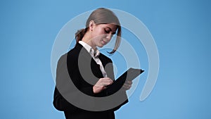 4k video of one girl who holding a tablet in his hands and showing thumb up over blue background.