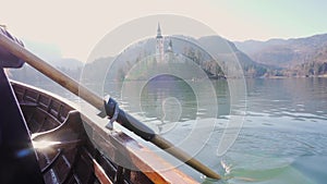 4K Video - A paddle in the water on a sunny day - Rowing the boat with island Lake Bled in the background- Lake Bled