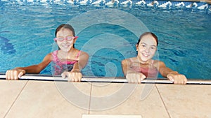 4k video of of two teenage girls in colorful swimsuits swimming in indoor pool