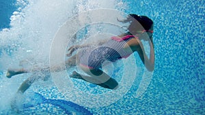 4k video of two teenage girls holding hands and jumping in swimming pool. View from under the water. Children playing