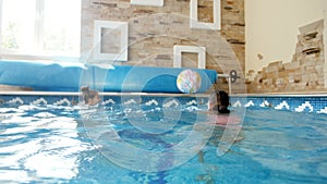 4k video of two teenage girls playing with colorful beach ball in the indoor swimming pool