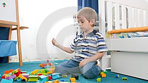 4k video of upset little boy got sad while playing with colorful building bricks and blocks on floor at his room