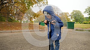 4k video of upset and sad little boy riding on bicycle at park on cold rainy autumn day