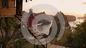 4K video of woman pink dress stand of tree house. Nusa penida, Bali, indonesia.