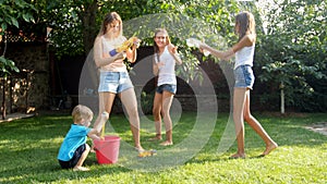 4k video of young mother having water guns battle with her children on backyard