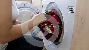 4k video of young woman in jeans taking out wet clean clothes from washing maching after laundry has finished