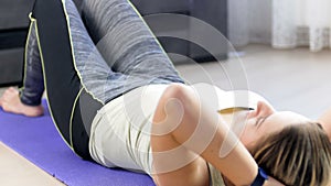 4k video of young woman lying on fitness mat using smart watch to measure her body parameters before doing abdomen