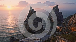 4K view of hidden Praia Da Ursa - Ursa Beach, Sintra, Portugal. Two huge rocks raisng in evening golden sunset light at