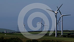 4K wind turbines in blue sky summer day power lines for electricity in background UK