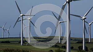 4K wind turbines hedgerows in farmers field blue sky summer day UK