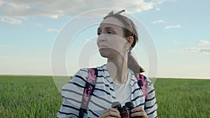 4K. A woman looks through binoculars. Standing in an endless green field