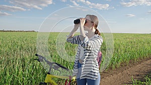 4K. A woman looks through binoculars. Standing in an endless green field