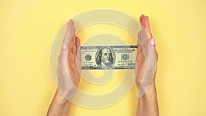 4k Women`s hands clap and a american 100 dollar bill appears in them. Yellow background.